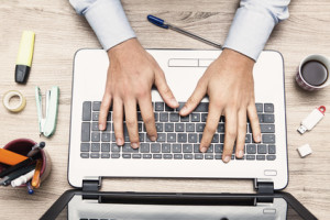 mani di uomo al alvoro sulla tastiera di un notebook informatico